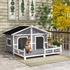 Gray and white cabin-style wooden dog house with spacious deck and asphalt roof outdoors
